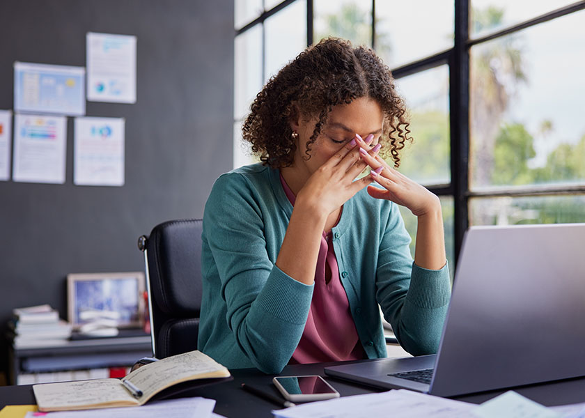 Frustrated woman holding hands to her face while looking at computer screen.